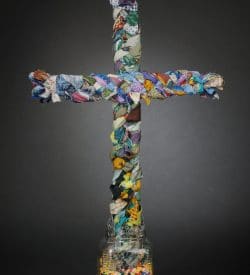 This is a 3-d cross made of fabric, wood, glass and beads.