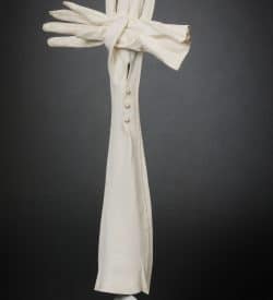 This is a 3-d cross made of White leather gloves, wood and wire and paint.