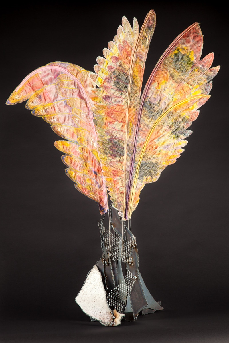 Welded steel base erupts into coloful delicate looking fabric wings.